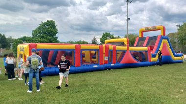 Toronto, ON, Kanada - 9 Eylül 2025: İnsanlar şişme bir engelli parkurun etrafında toplanıp açık havanın tadını çıkarıyorlar..