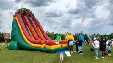 Toronto, ON, Kanada - 9 Eylül 2025: Büyük bir şişme slayt çocukları açık hava etkinliğinde eğlendiriyor, yaz eğlencesi için mükemmel..