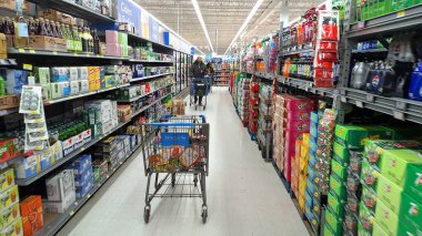 Toronto, ON, Kanada - 13 Mart 2026: Alışverişçinin biri, iyi stoklanmış bir süpermarketin koridorlarında bir el arabasını itip çeşitli içecek ve atıştırmalıklar seçiyor..