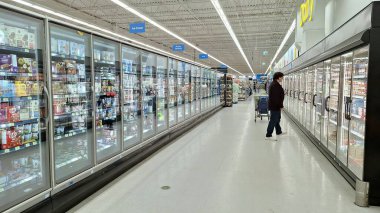 Toronto, ON, Kanada - 13 Mart 2026: Bir süpermarkette dondurucu koridorlarında donmuş gıda bölümleriyle yürüyen insanlar.