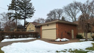 Toronto, ON, Kanada - 13 Mart 2026: Sakin bir banliyö caddesi kışın son kalıntılarını gösteriyor, karlar iyi korunmuş evlerin yanında..