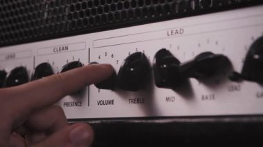 Tüp gitar amplifikatörü kafa topuzları. Bir adam canlı performansta gitar çalan bir seyirciyi sallayacak, sahnede bir konser verecek ve amfiyi açacak, kabloları takacak ve ayarlayacak.
