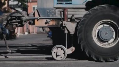 Muazzam tekerlekleri olan bir traktör, demiryolu boyunca sürüyor ve yük vagonunu sürüklüyor, duruyor. İsteyenlere ürün göndermek için nakliye noktasında kargo taşımacılığı. Teslimat işi devam ediyor.  