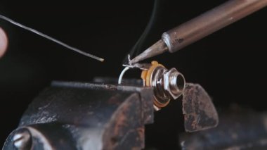 Tamirci elektrik parçalarını, kabloları lehimliyor lehim ve ısıtma demiri kullanarak teli düzgünce tamir ediyor.