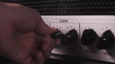 Tüp gitar amplifikatörü kafa topuzları. Bir adam canlı performansta gitar çalan bir seyirciyi sallayacak, sahnede bir konser verecek ve amfiyi açacak, kabloları takacak ve ayarlayacak.