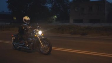 Motosikletli bir kadın, motorcu kaskı takıyor - güvenlik en önemli şey, gece caddesinde geziniyor. Bisikletli bir kadın sıkışıklıktan kurtuldu. Motosiklet özgürlüktür. Trafik sıkışıklığı yok. Rüzgâr.