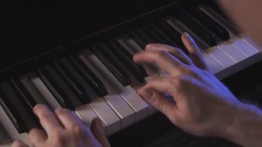 Müzisyen canlı performans sırasında piyano çalar. Sağ el mavimsi bir yıldırımda tuşları çalıyor. Konser izleyicilerinde klavyeci. Piyano çalan bir piyanist midi dijital piyano notaları alır.