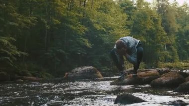 Ormanda egzersiz yapıyorduk. Bir adam sabah ormanındaki eğitimden sonra başını serinletmek için tatlı suyu dereden alır. Sağlıklı, sağlıklı, sağlıklı bir yaşam tarzı. Spor, kardiyo, egzersiz konsepti