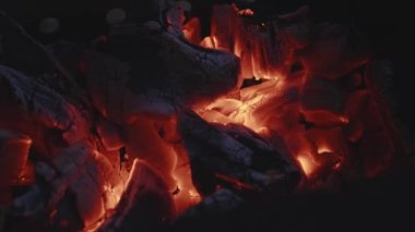 Karanlıkta yanan kömür, yanan kömür kırmızı kıvılcımlar ve ateş saçıyor. Mangal için mangal kömürü. Şöminenin önünde rahatlamak için güzel bir manzara. Kaybolan bir şenlik ateşinin sıcaklığı. Kamp ateşine yakın çekim