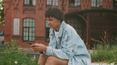 Koyu renk saçlı güzel bir kız sosyal medyada akıllı telefon kullanıyor, haberleri kontrol ediyor, mobil oyunlar oynuyor ya da sokaklarda mesajlar yolluyor. Milenyum bayanı. Bulanık şehir arkaplanı