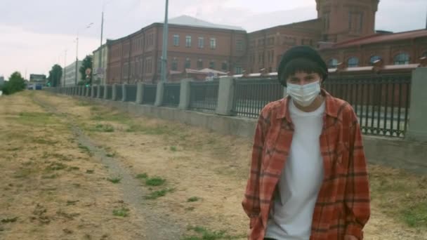 路上で保護医療面マスクを被った美しい黒髪の少女の撮影 女性は社会的距離や隔離の練習から解放されます 都市を背景に — ストック動画