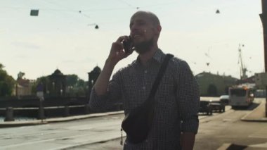 Kel sakallı adam akıllı telefon kullanarak sosyal medyada sörf yapıyor, haberleri kontrol ediyor, oyun oynuyor, iş görüşmesi yapıyor ya da güneşli bir günde sokakta mesaj yazıyor. Bulanık şehir arkaplanı