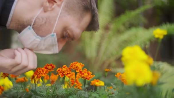 Tagen Medicinsk Skyddsmask Från Mannen Som Sniffar Rödaktiga Orange Blommorna — Stockvideo