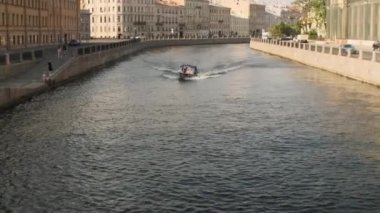 Dik kıyıda yüzen bir gemi, giden bir tekne. Su yüzeyi dalgalanması. Küçük dalgalar şehre doğru giden kanalda akan su yayıyor. Karanlık derin nehir. İnsanlarla dolu bir rota.
