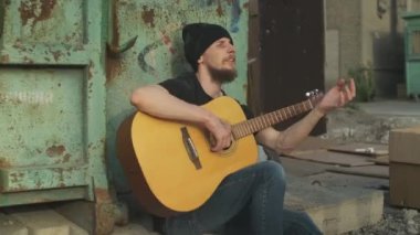 Sokaktaki evsiz adam çöp konteynırının yanında gitar çalarak para kazanıyor. Yıkılmış bir insan, yoksulluk, sefalet, işten çıkarılma, kovulma, kovulma. Sosyal sorunlar, işsizlik kavramı