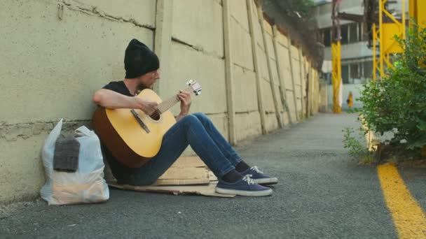 Dakloze Man Met Bezittingen Straat Zittend Bij Het Hek Gitaar — Stockvideo