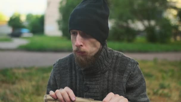 路上でパラペットに座っている所持品を持つホームレスの男は 仕事を探している 貧困と惨めさに陥り解雇され解雇され解雇された 社会問題失業概念 — ストック動画
