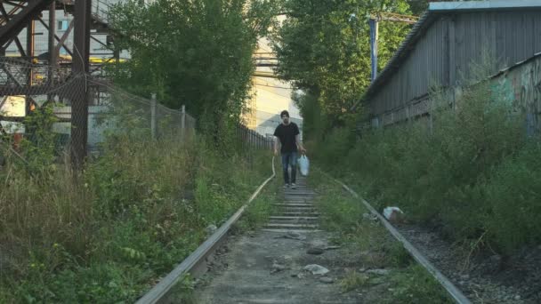 所有物のあるホームレスの男は 鉄道に沿って行く飢えの塊 貧困や惨事に巻き込まれ解雇され解雇され焼かれました 社会問題失業概念 — ストック動画