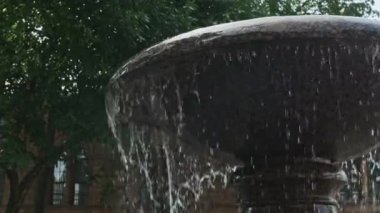 Antik şehir mimarisinin güzel manzarası. Park çeşmesi su kusuyor. Çeşmenin su sıçratma manzarası. Çeşmeden akan su binlerce su damlasına çarpıyor..