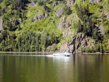 Dağlar ve ormanlar boyunca nehirde yüzen bir tekne. Yolcu gemisi.
