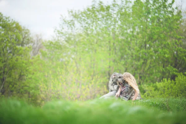 Κορίτσι με το καιρό φως μαλλιά να καθίσει με ένα τεράστιο σκυλί γκρι — Φωτογραφία Αρχείου