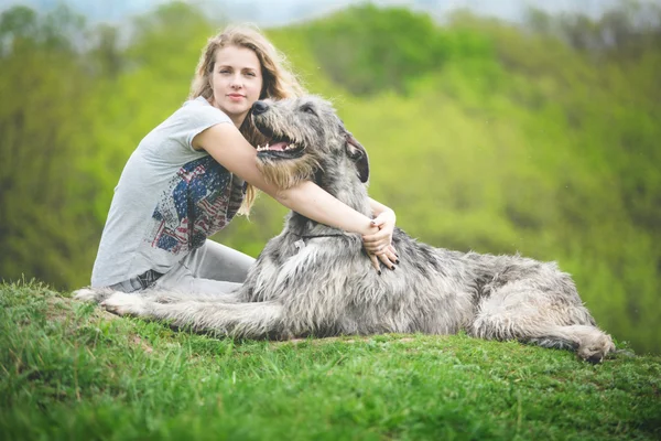 Κορίτσι με το καιρό φως μαλλιά αγκαλιά ένα τεράστιο σκυλί γκρι — Φωτογραφία Αρχείου