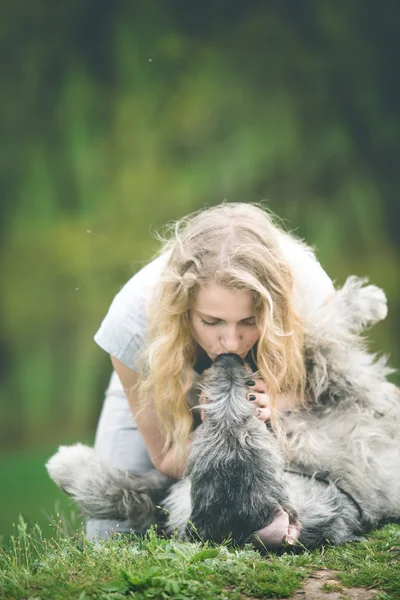 Mädchen mit den langen hellen Haaren küsst einen riesigen grauen Hund — Stockfoto