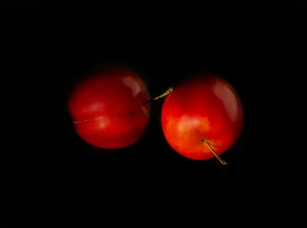 Dua plum merah diisolasi pada latar belakang hitam — Stok Foto