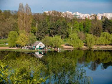 Şehir parkındaki göl kıyısındaki tekne istasyonu. Ev ve etrafındaki orman gölün suyuna yansıyor..