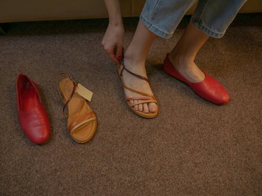 Kadın ayakkabısı mağazası. Yazlık sandalet deneyen bir kızın yakın çekimi..