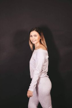 Siyah arka planda örülü açık renk takım elbiseli genç bir kız..