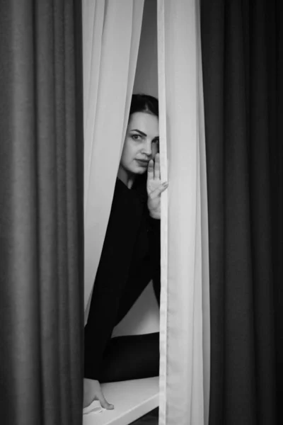 Zwart-wit foto van een meisje in het raam, tule, gordijn. — Stockfoto