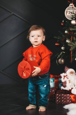Yeni yıl hediyesi olan küçük mutlu çocuk. Neşeli bir ruh hali. Çok güzel gülümseyen bir çocuk, çocuk hediyeyle mutlu.