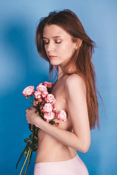 Menina morena nua segurando flores. beleza natural. sobre um fundo azul — Fotografia de Stock