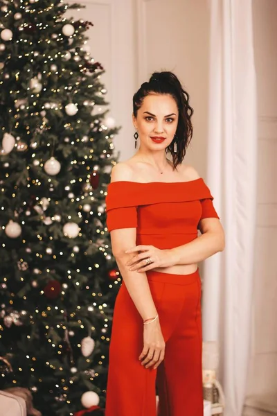  Kızın yeni yıl fotoğraf seansı. Kırmızı elbiseli bir kız güzel bir Noel ağacının arka planında