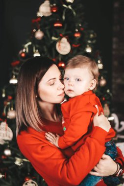 Genç mutlu anne ve oğul yeni yılda. Anne ve oğul yeni yıl ağacının yanında sarılıyor.
