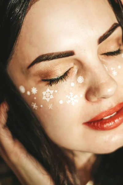 girl with New Years makeup. snowflakes on the cheeks of a girl