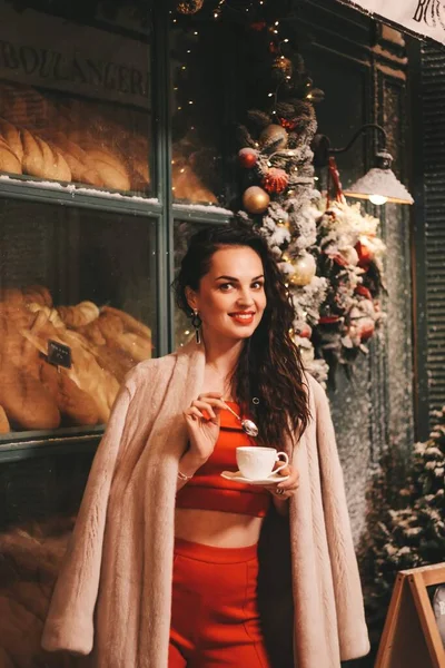 Nyårsfotografering av flickan. flicka i en röd kostym mot bakgrund av en vacker julgran — Stockfoto