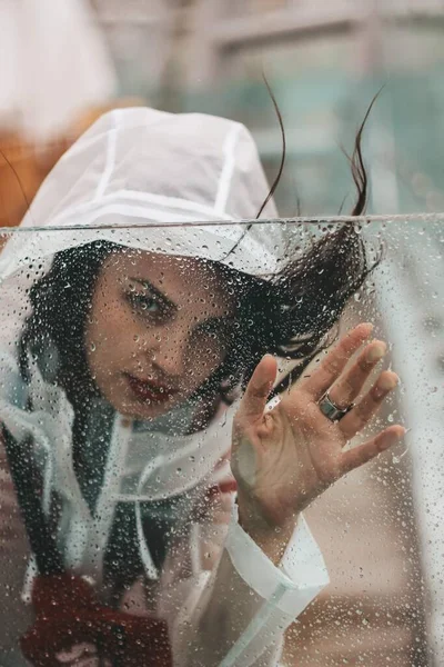 レインコートの雨の中の少女。ガラスへの落下. — ストック写真