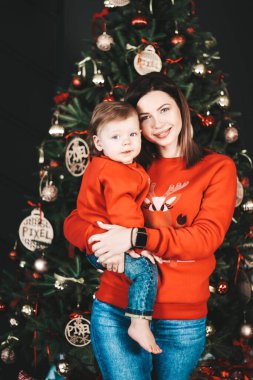 Genç mutlu anne ve oğul yeni yılda. Anne ve oğul yeni yıl ağacının yanında sarılıyor.