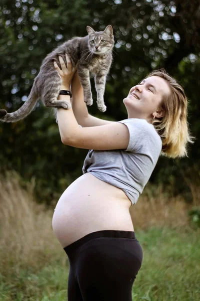 Těhotná dívka s kočkou v náručí. bezstarostný život. šťastné těhotenství. — Stock fotografie