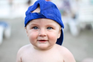 Mavi şapkalı yeni yürümeye başlayan bebek. Neşeli bir çocukluk. Dinlen, deniz, sahil. dikkatsizlik..