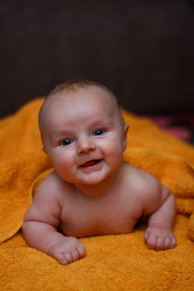 Küçük bir bebeğin ev fotoğrafı. Yeni doğmuş küçük bir bebek havlunun üzerinde yatıyor. Küçük çocuk. Evdeki sevimli çocuk..