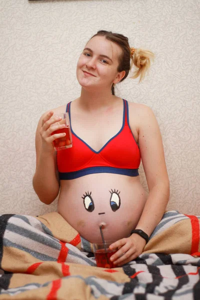 Fille enceinte avec un drôle de visage dessiné sur le ventre. — Photo