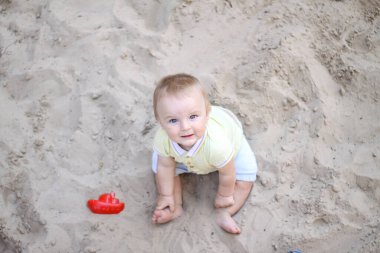 Küçük çocuk kumda oynuyor. Bebek kumla oynuyor. Yaz tatili. Güneş, deniz, sahil, kum. Dinlen, çocukluk.