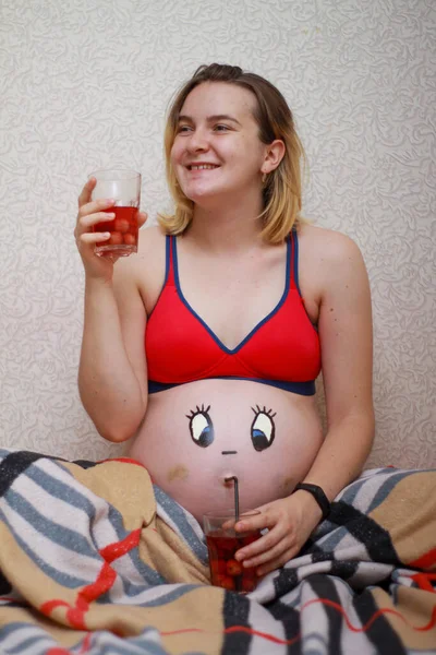 Fille enceinte avec un drôle de visage dessiné sur le ventre. — Photo