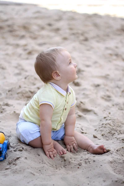 砂の中で遊んでいる男の子。赤ちゃんは砂と遊ぶ。夏休みだ。太陽、海、ビーチ、砂。休み子供時代. — ストック写真