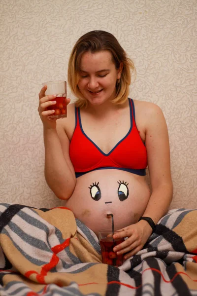 Fille enceinte avec un drôle de visage dessiné sur le ventre. — Photo