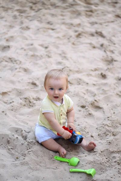 Um rapazinho a brincar na areia. O bebé brinca com areia. Descanso. Sol, mar, praia, areia. Descanso, infância. — Fotografia de Stock