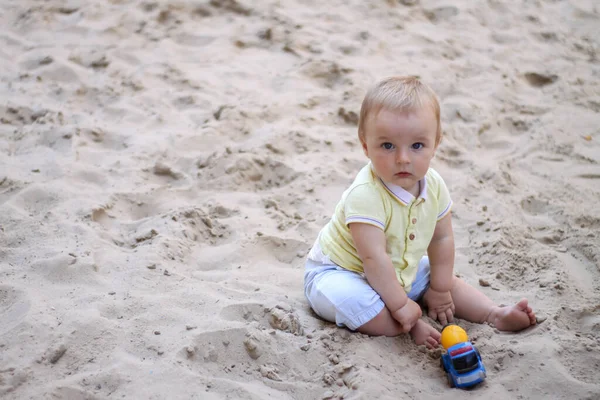 Um rapazinho a brincar na areia. O bebé brinca com areia. Descanso. Sol, mar, praia, areia. Descanso, infância. — Fotografia de Stock